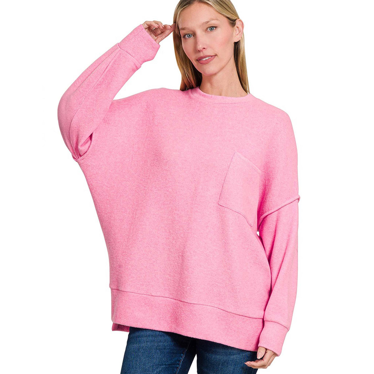 Woman wearing a candy pink cardigan and blue jeans on a white background