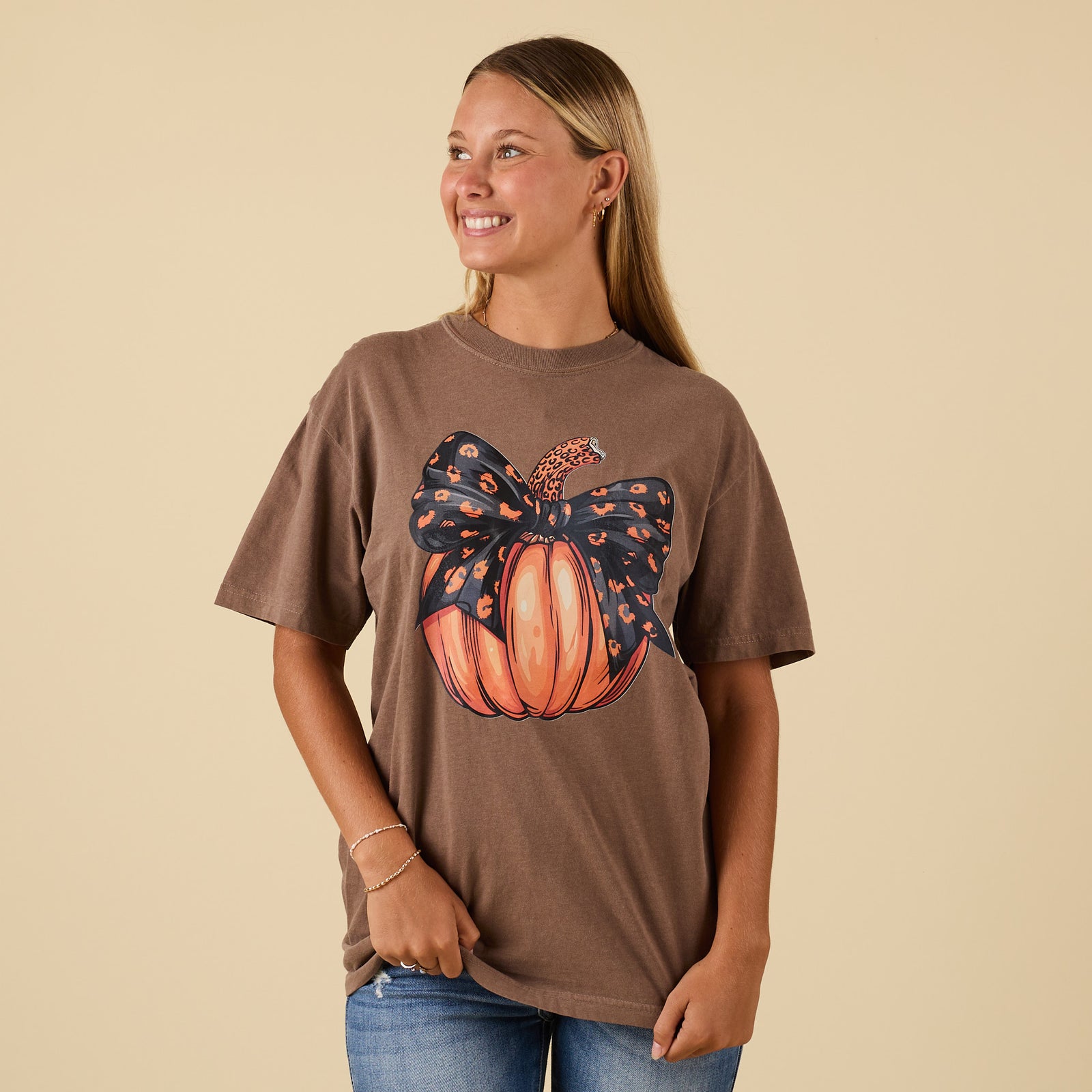 Front view of brown t-shirt featuring pumpkin with leopard-print bow graphic.