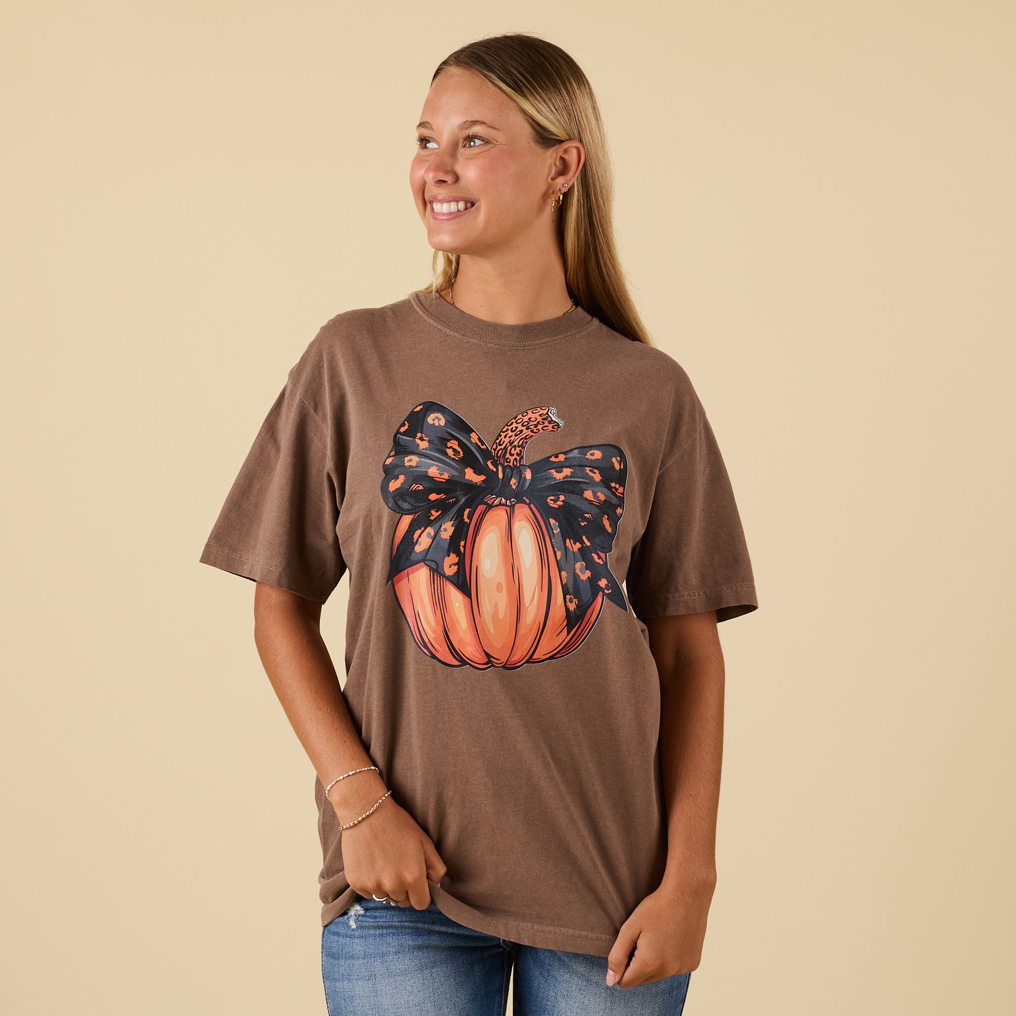 Front view of brown t-shirt featuring pumpkin with leopard-print bow graphic.