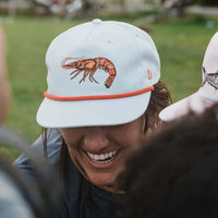 Woman smiling while wearing a Duck Camp hat.