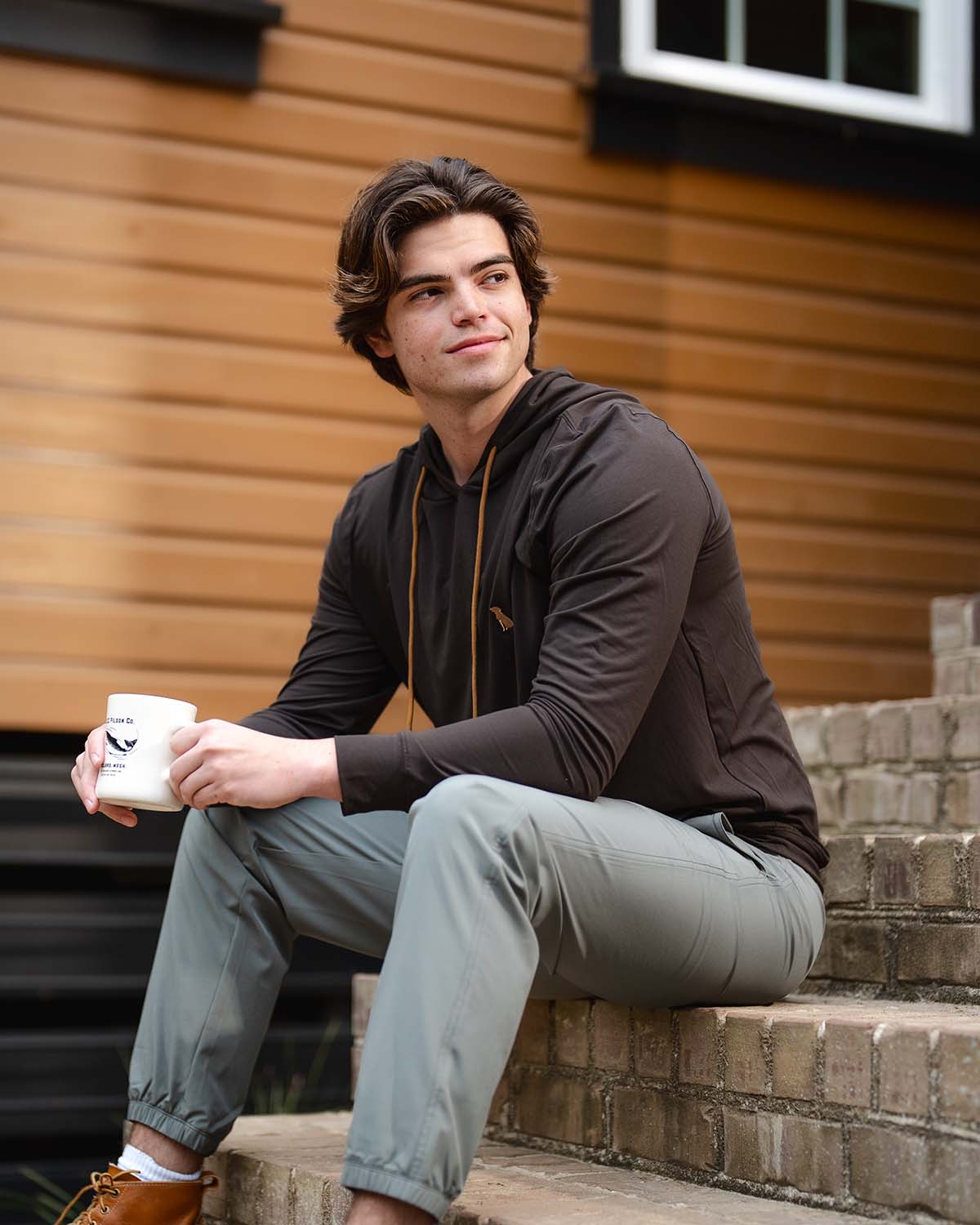 Man sitting on brick stairs holding a coffee mug.