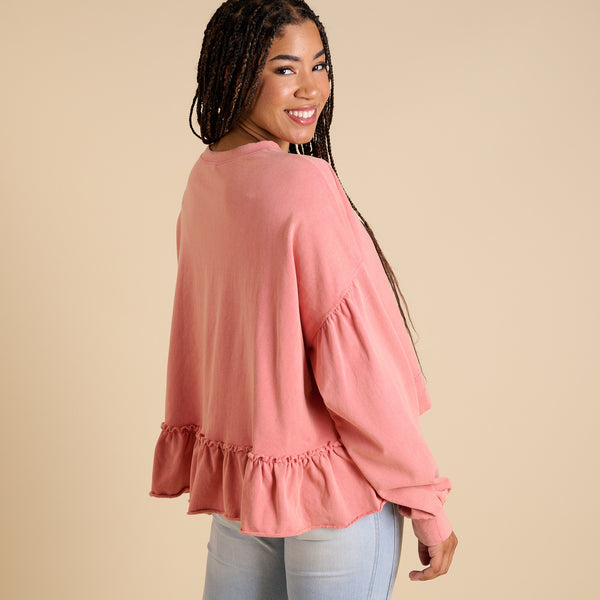 Woman wearing a pink blouse with ruffled details on a beige background