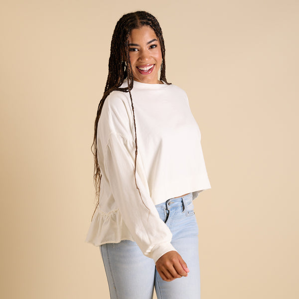  Woman wearing a white blouse with ruffled sleeves against a beige background