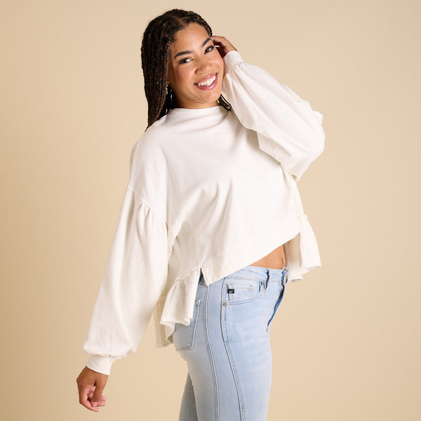  Woman wearing a white blouse and light blue jeans against a beige background