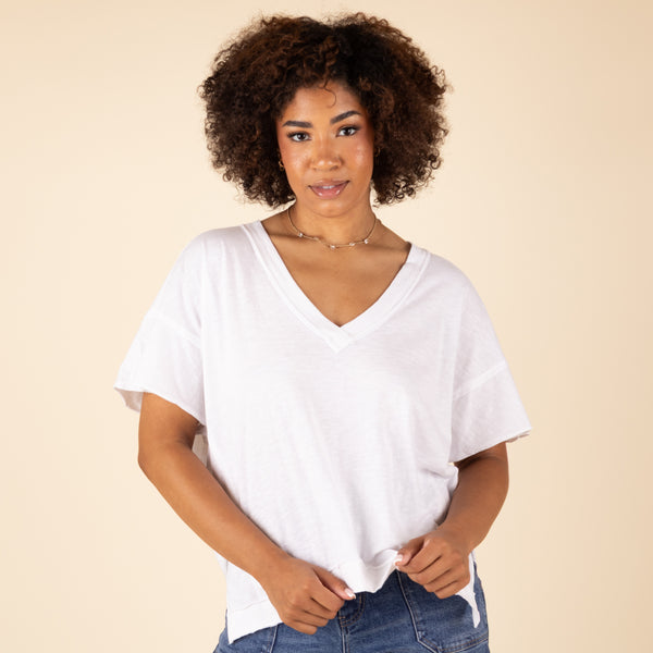  Woman wearing a white V-neck shirt against a beige background