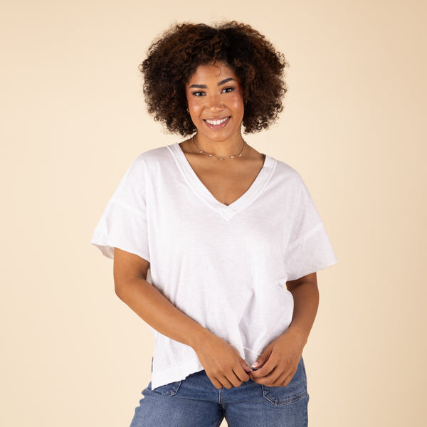  Woman wearing a white t-shirt and blue jeans against a beige background
