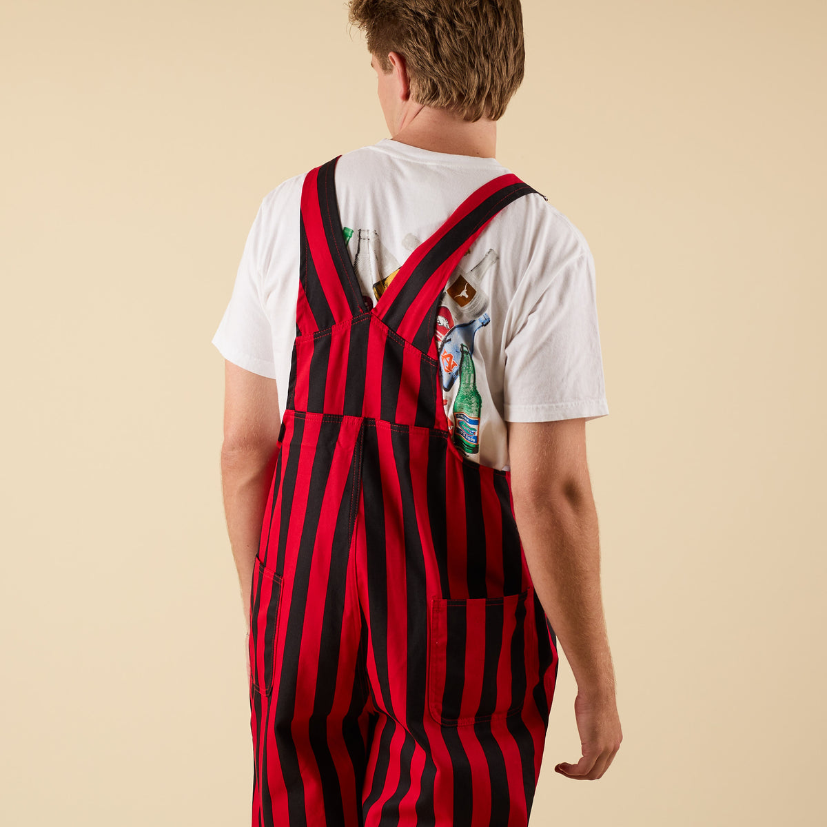 Back view of a man wearing red and black striped overalls.