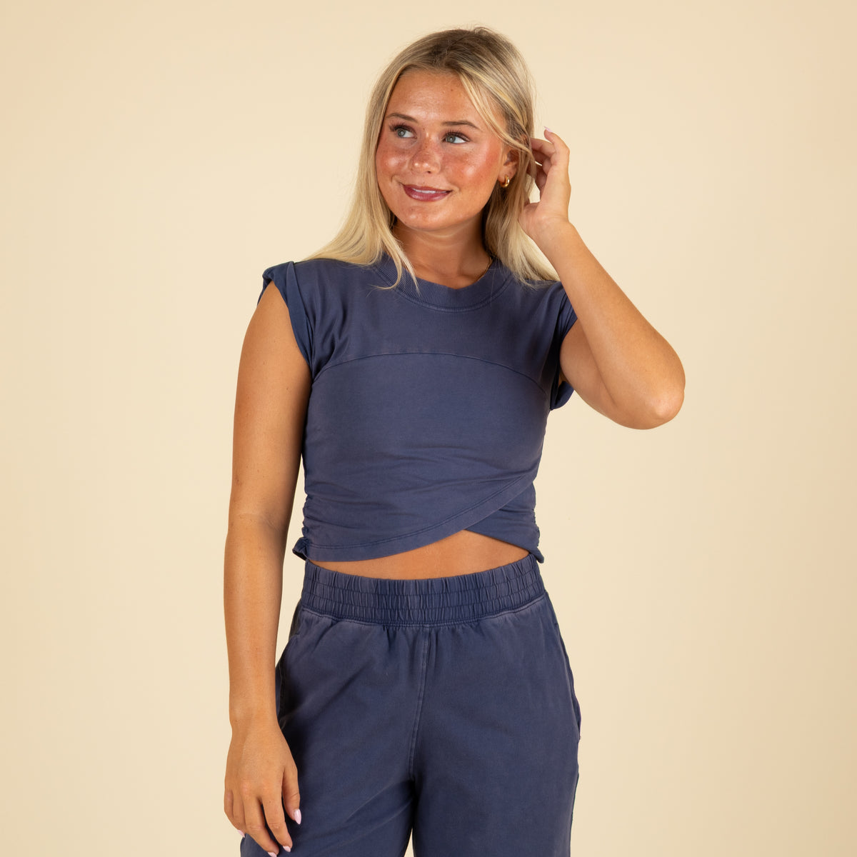 Close-up front view of navy twist-front crop top paired with matching wide-leg joggers, showing fitted waist and cap sleeves.