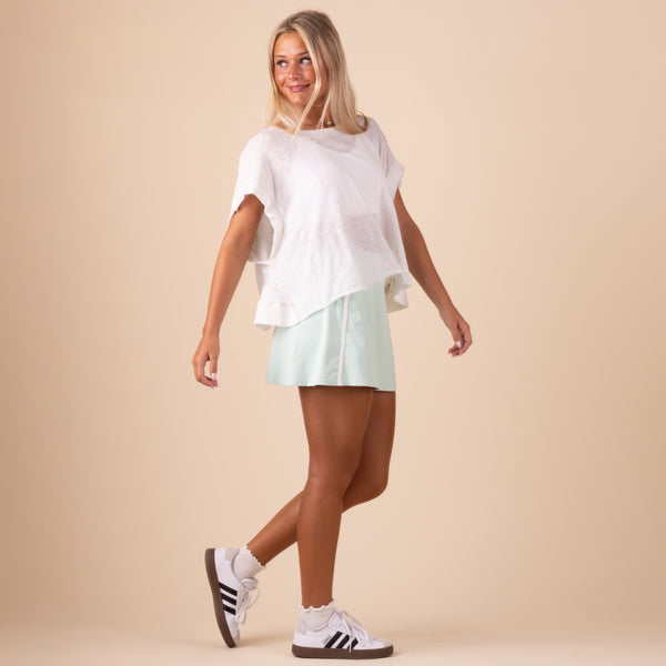 in studio front view Free People Movement Short Sleeve My Time Tee – lightweight, relaxed-fit t-shirt with an open-back design for breathability. Color white.