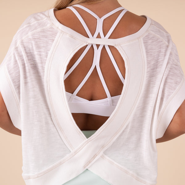 in studio back view Free People Movement Short Sleeve My Time Tee – lightweight, relaxed-fit t-shirt with an open-back design for breathability. Color white.