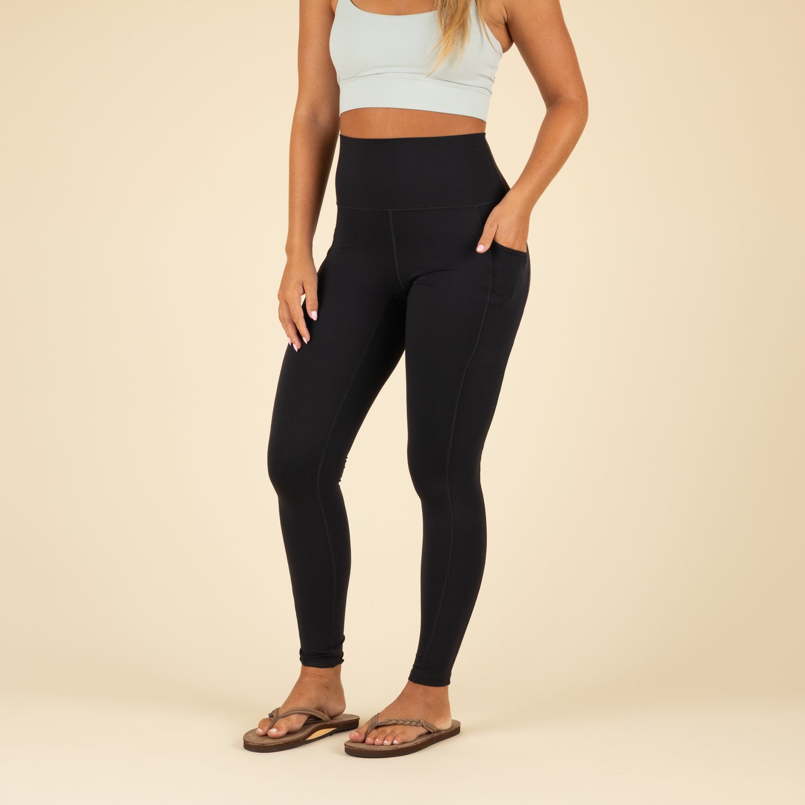 Person wearing black leggings and a light blue sports bra on a beige background