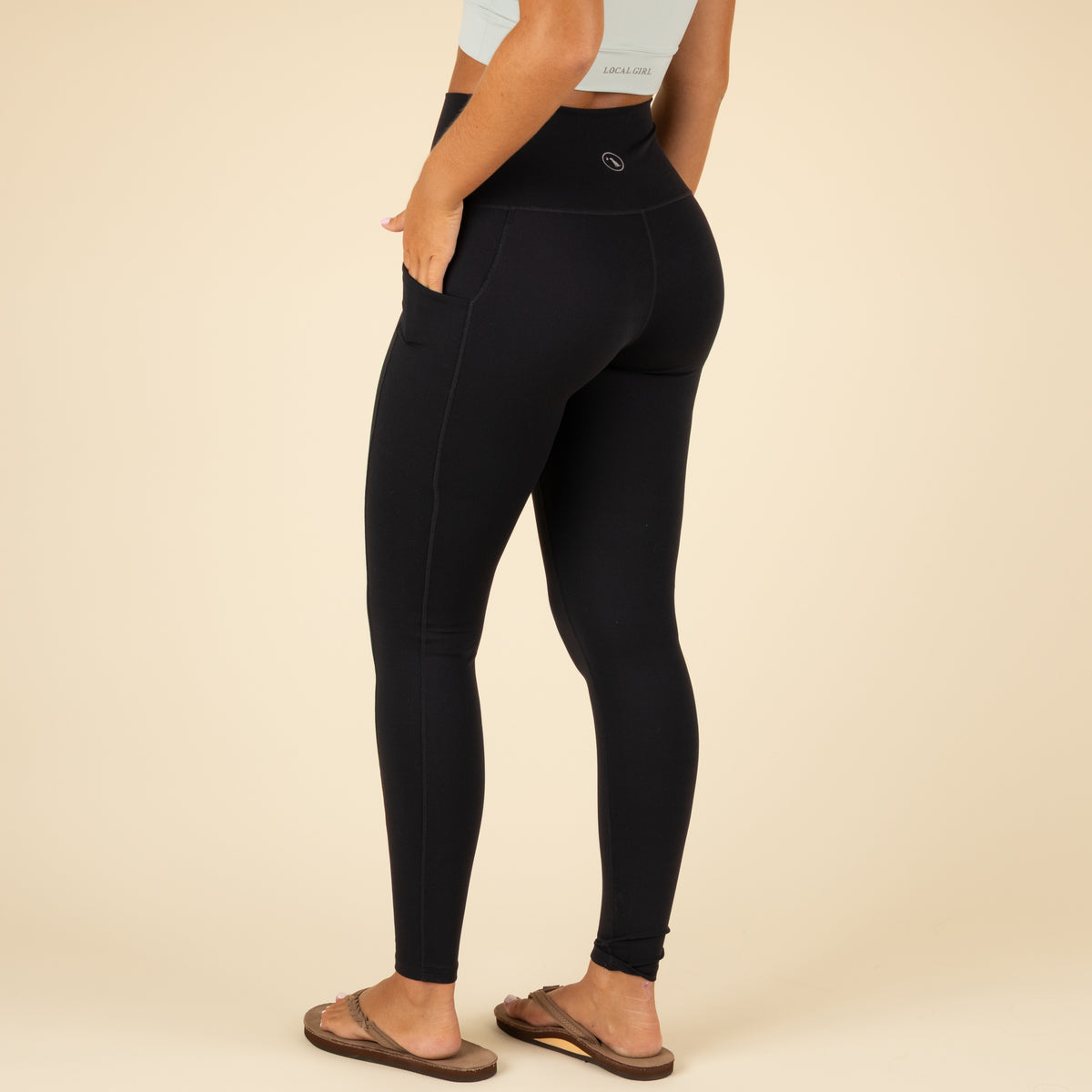 Person wearing black leggings on a beige background