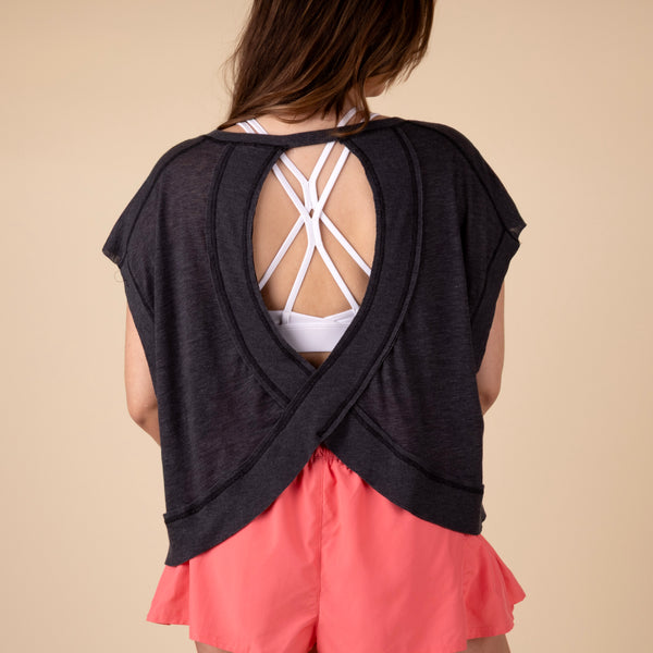 in studio back view Free People Movement Short Sleeve My Time Tee – lightweight, relaxed-fit t-shirt with an open-back design for breathability. Color black.