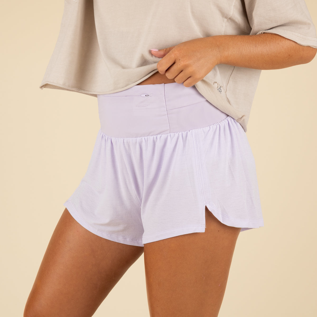 Person wearing light purple shorts on a beige background
