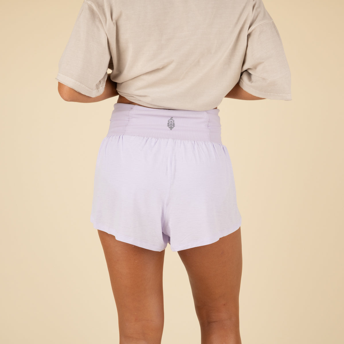Person wearing light purple FP Movement shorts on a beige background