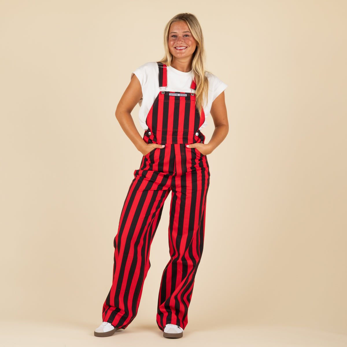 Person wearing red and black striped overalls on a beige background