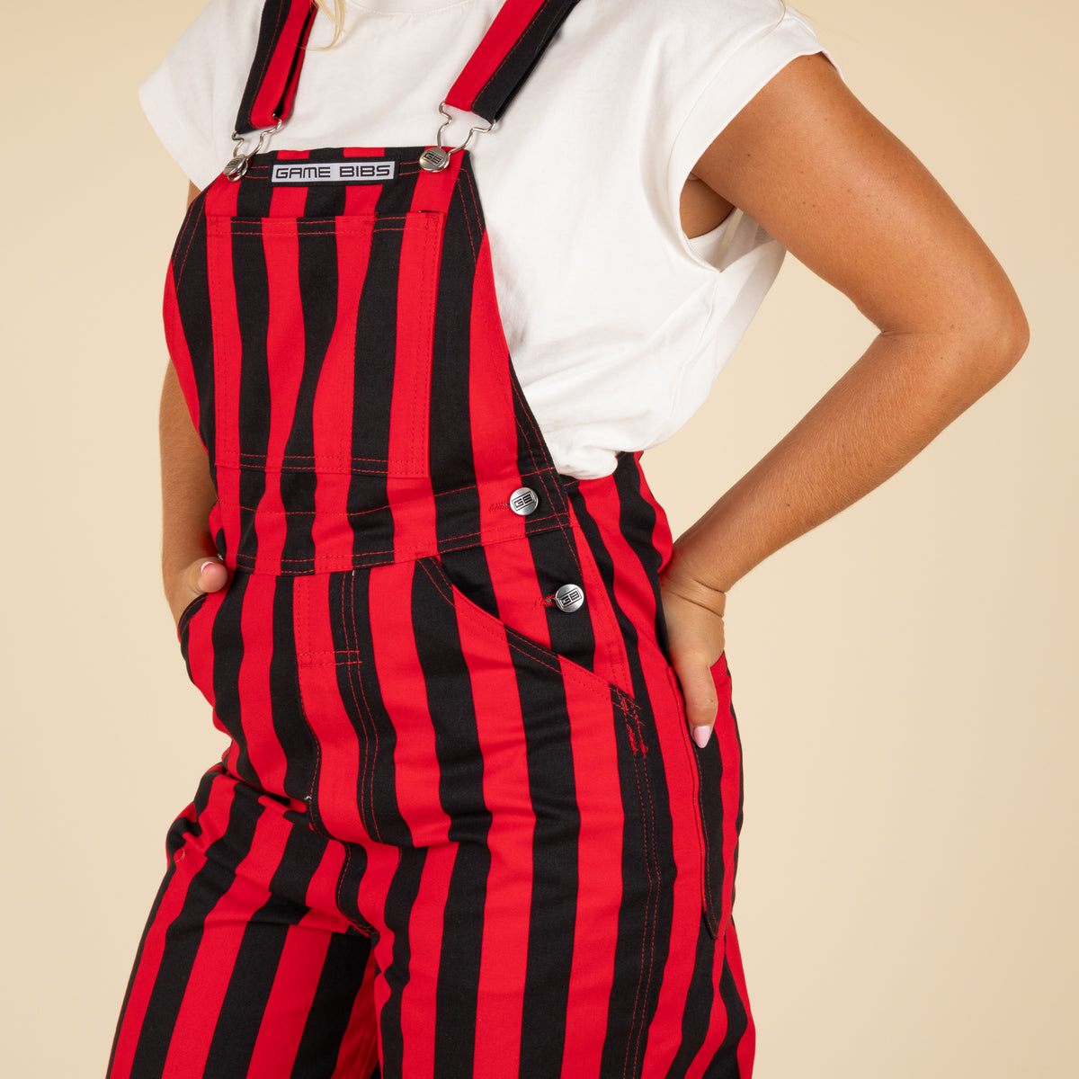 Person wearing red and black striped overalls with a plain background