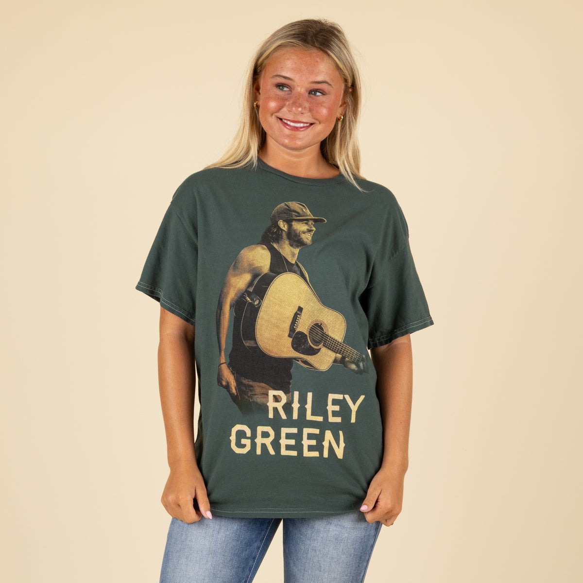 Riley Green tour t-shirt worn by model, featuring a large front graphic of Riley Green holding a guitar with his name in bold text.