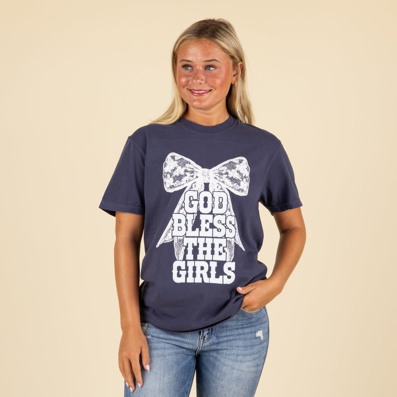 Woman wearing a navy blue t-shirt with a white bow and text design on a beige background