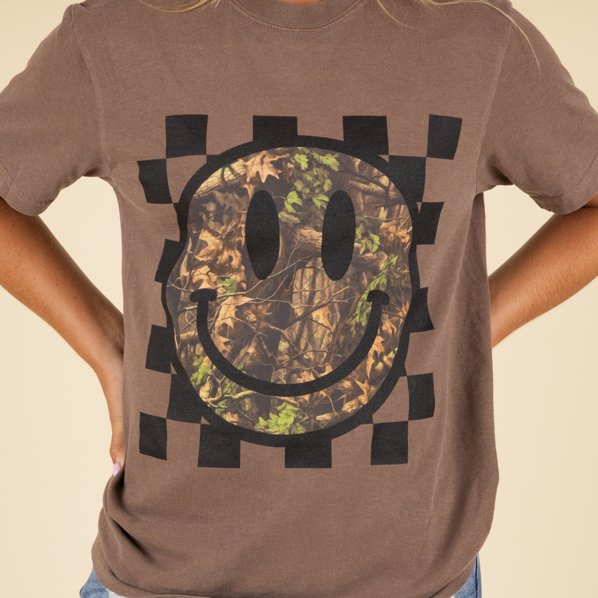 Brown t-shirt with a camouflage smiley face design on a beige background