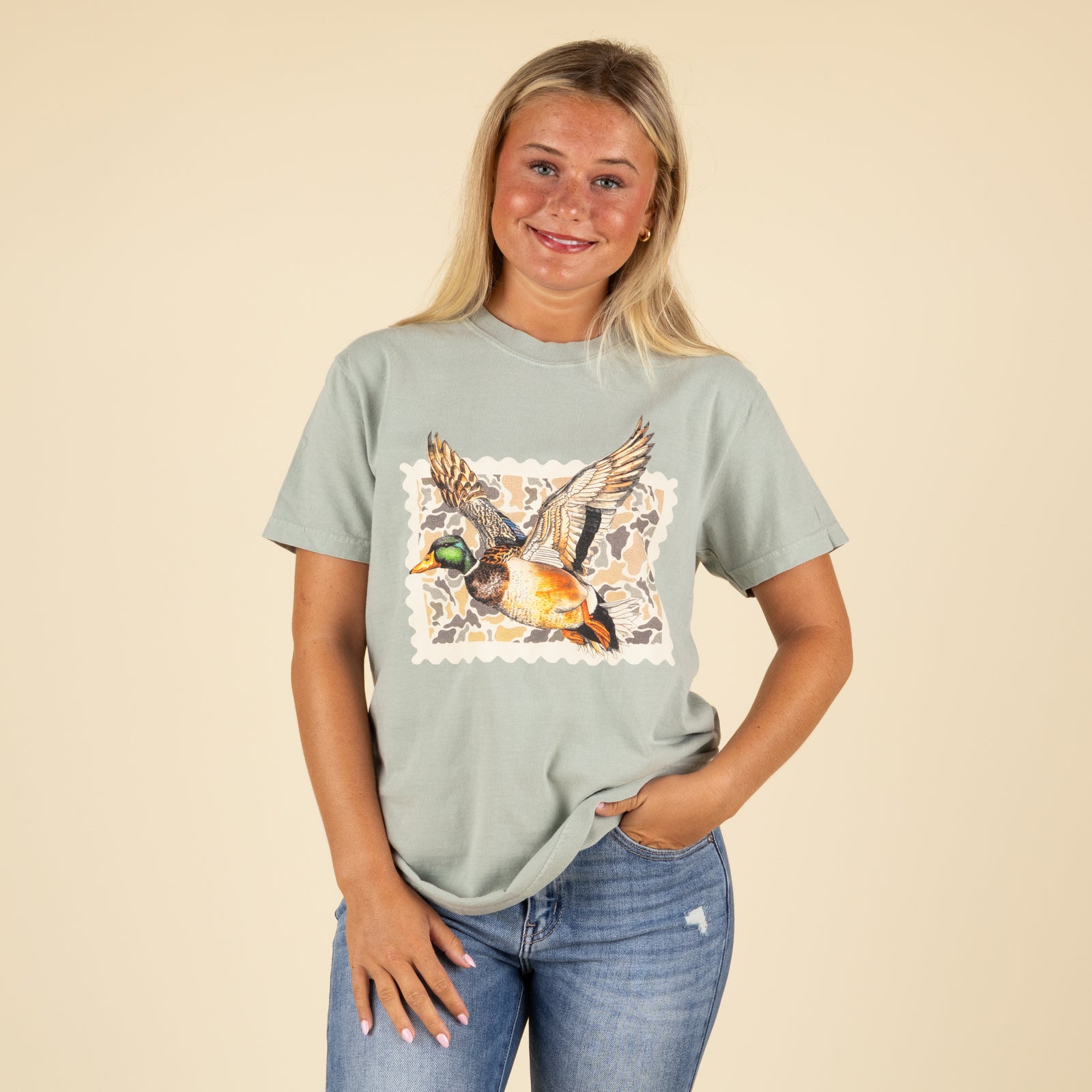 Woman wearing a light green t-shirt with a duck graphic on a beige background