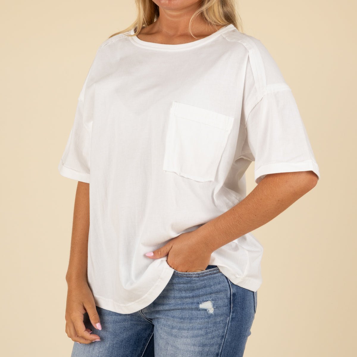 Side angle close-up of a white oversized pocket t-shirt styled with light blue denim jeans.