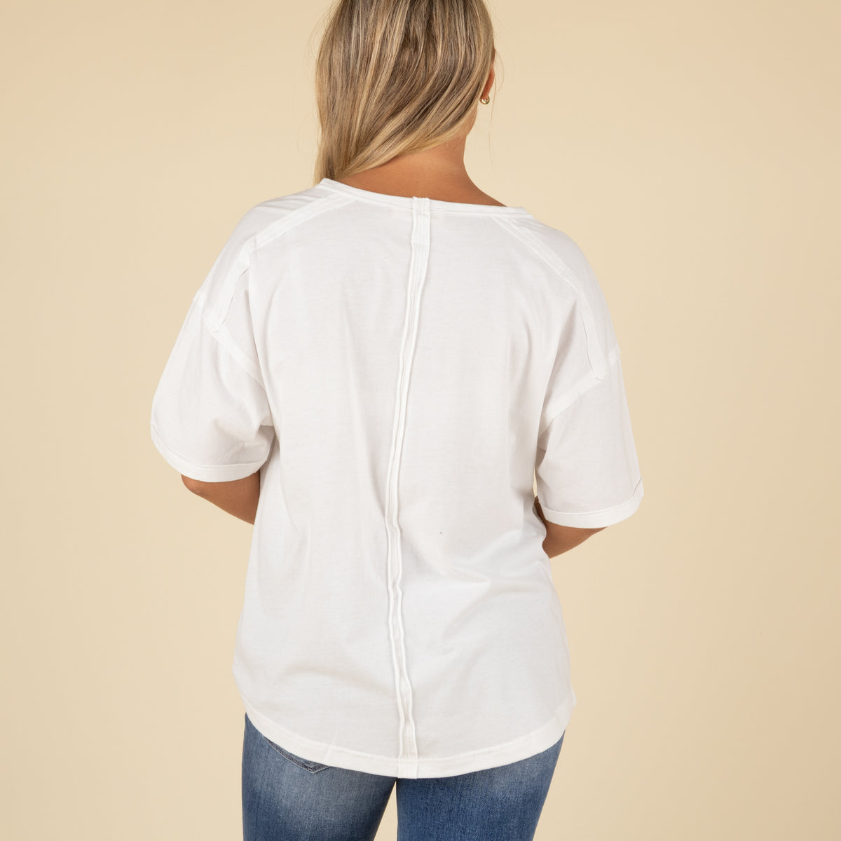 back view of a white oversized pocket t-shirt styled with light blue denim jeans.