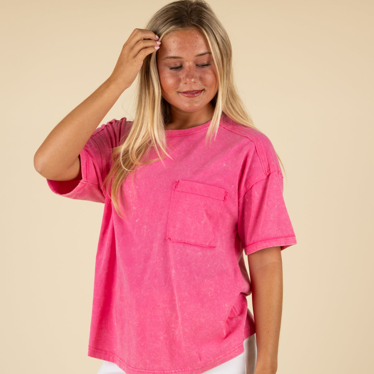 Front view of a woman wearing a hot pink oversized t-shirt with a washed finish and chest pocket.