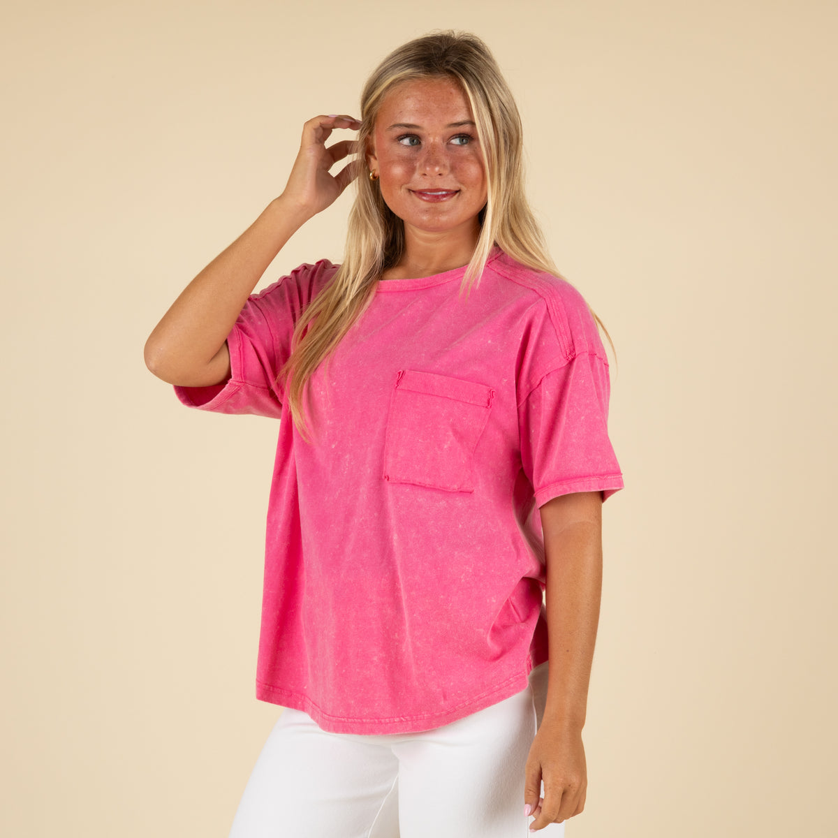 Front view of a woman wearing a hot pink oversized t-shirt with a washed finish and chest pocket.