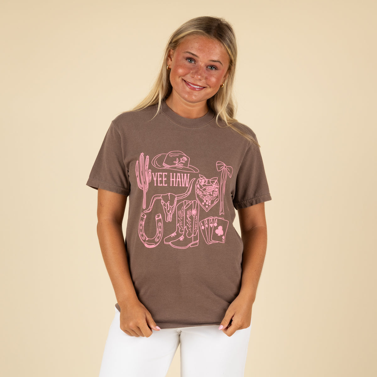 Person wearing a brown t-shirt with pink graphic design on a beige background