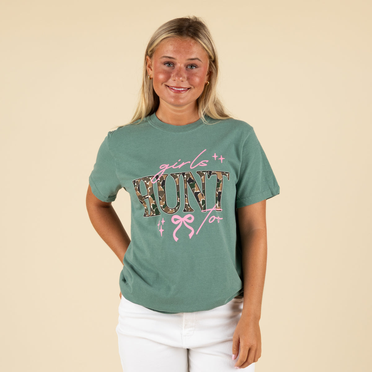 Woman wearing a green t-shirt with 'girl hunt' design on a beige background