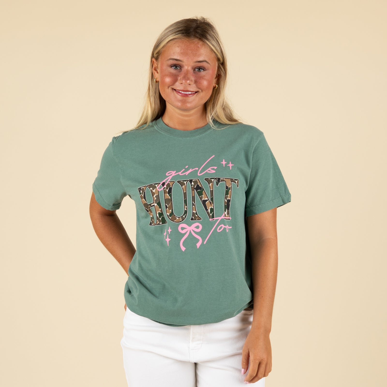 Woman wearing a green t-shirt with 'girl hunt' design on a beige background