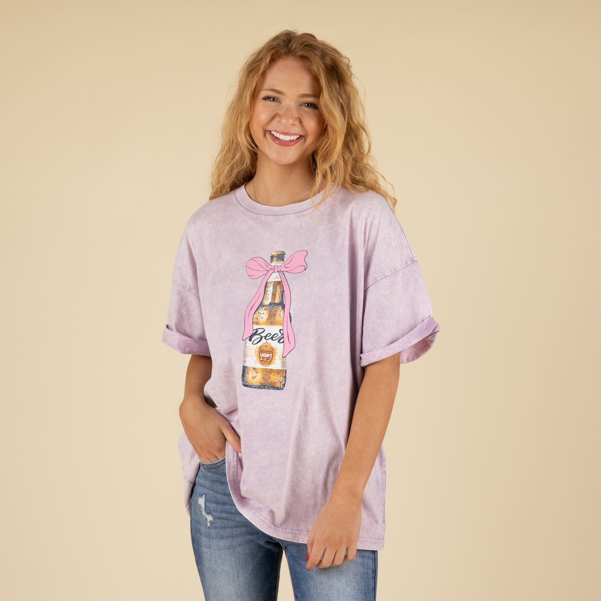 Woman wearing a light purple t-shirt with a graphic design on a beige background