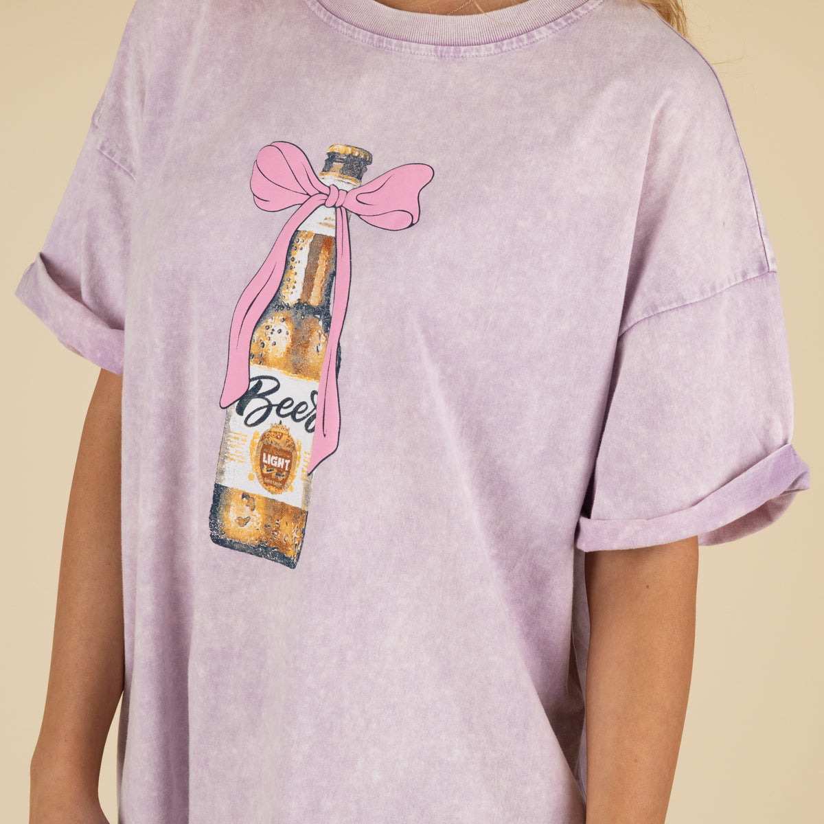 Person wearing a light purple t-shirt with a beer bottle graphic and 'Beer' text on a beige background