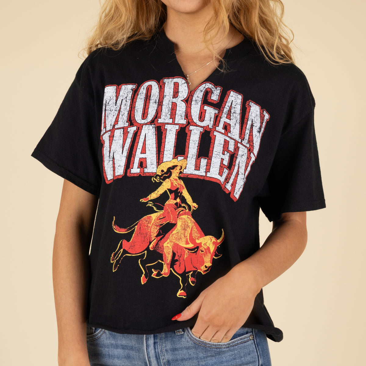 Person wearing a black t-shirt with 'Morgan Wallen' graphic design on a beige background