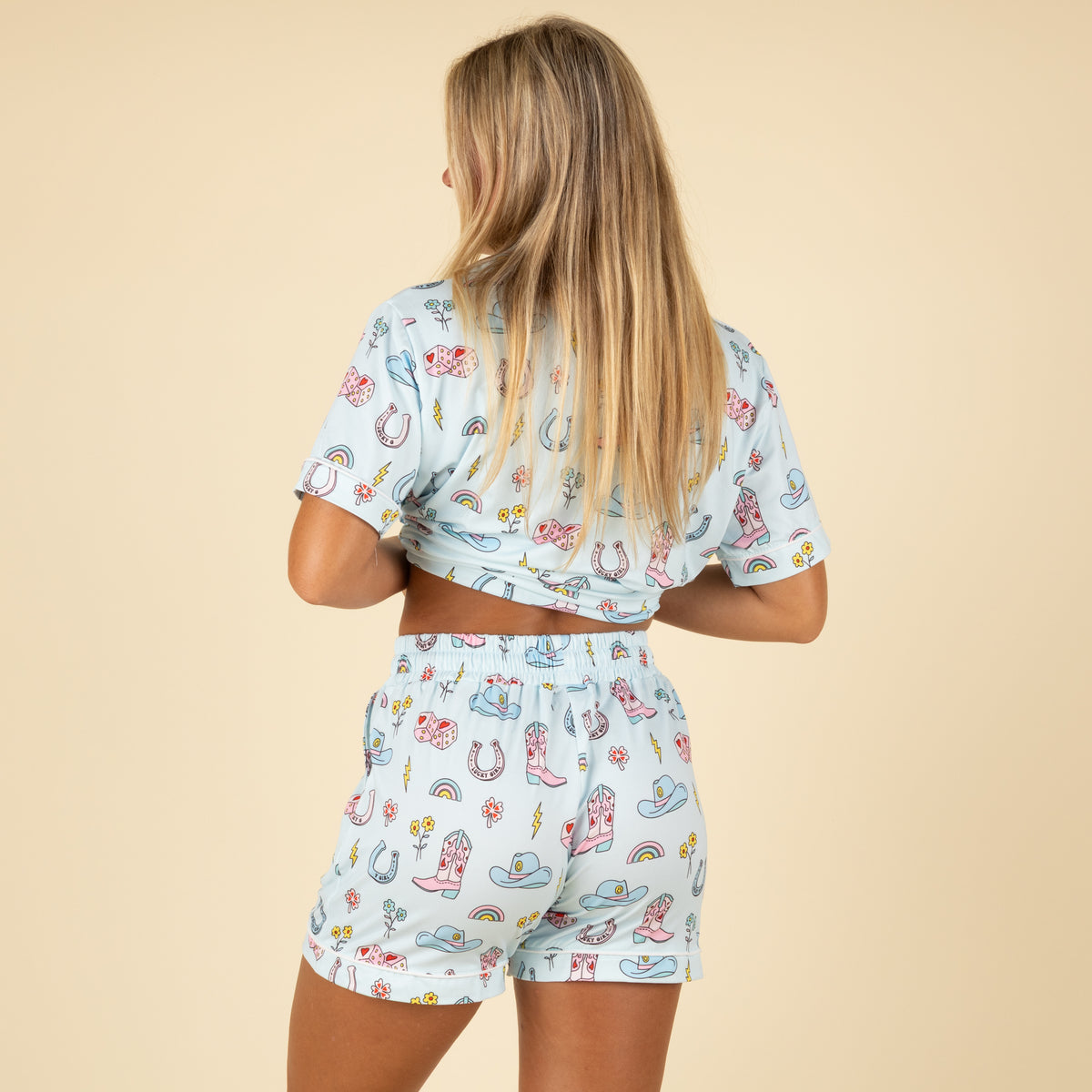 Back view Light blue pajama shorts with all over pattern of colorful western themed graphics.