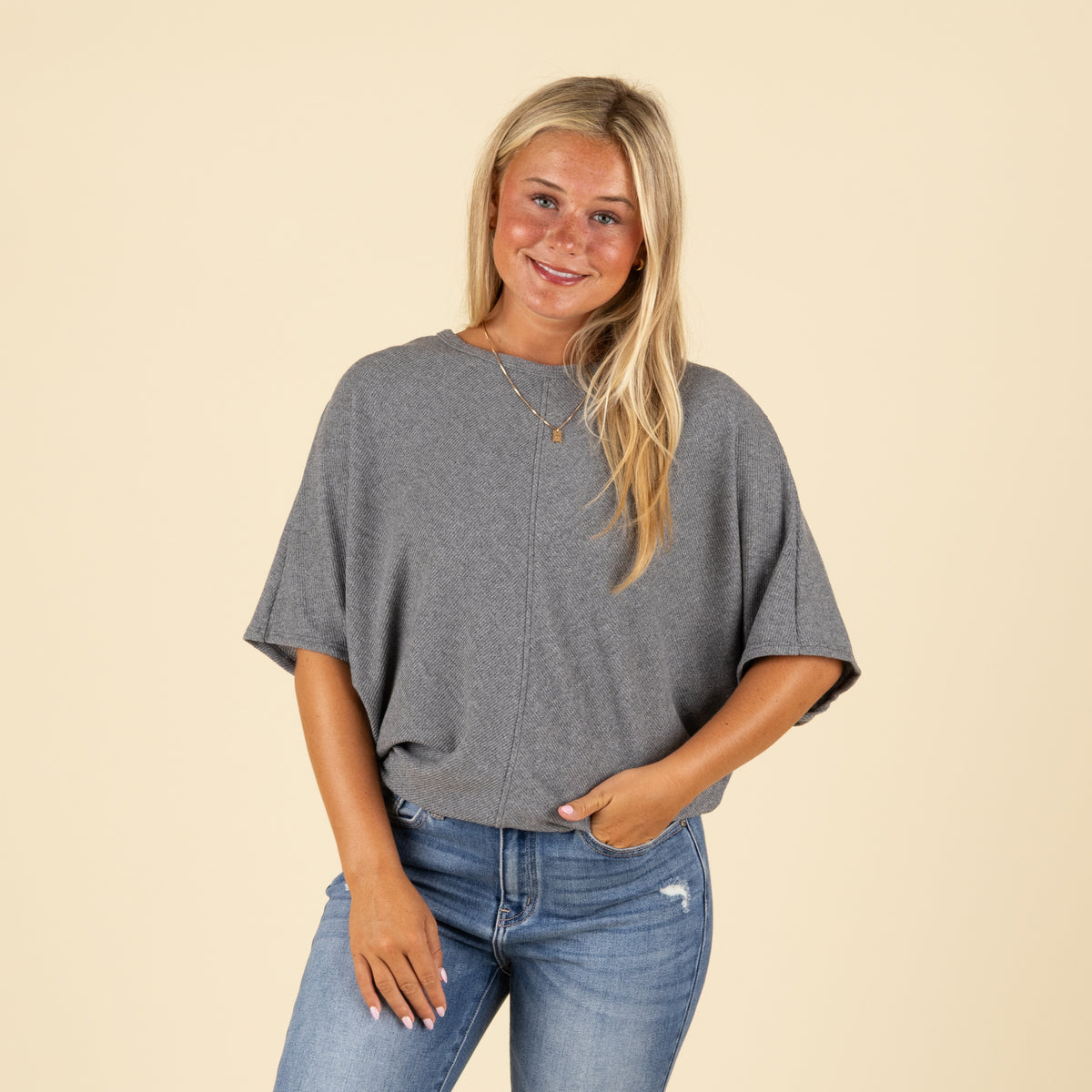 Front view of model wearing charcoal grey ribbed cocoon top styled with denim jeans.