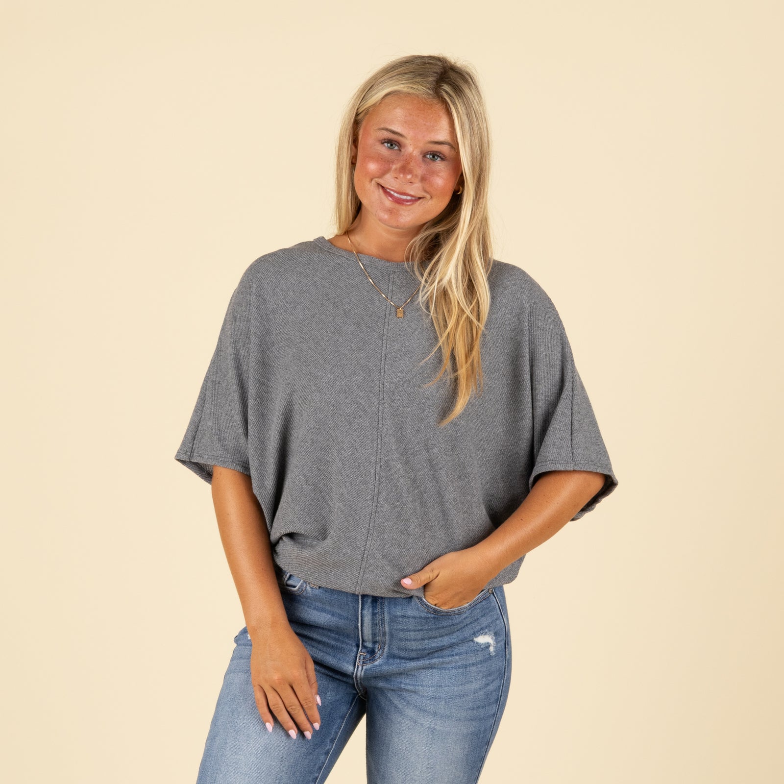 Front view of model wearing charcoal grey ribbed cocoon top styled with denim jeans.