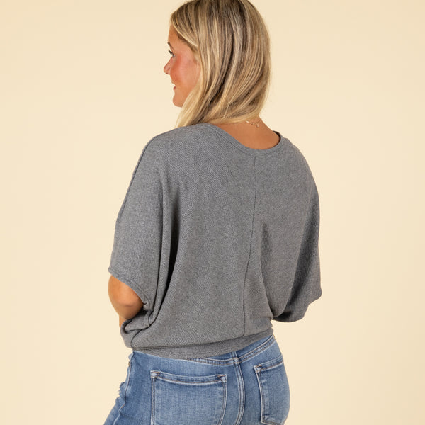  Close-up side view of grey cocoon top’s ribbed sleeve and soft texture.