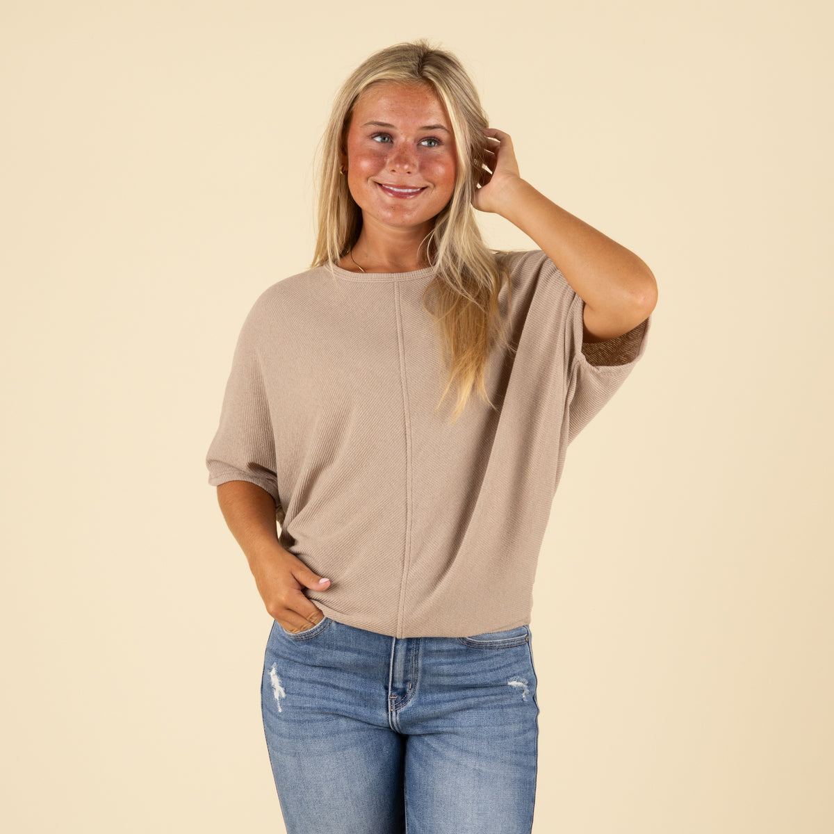 Front view of model in taupe ribbed short sleeve cocoon top with curved hem and subtle texture.