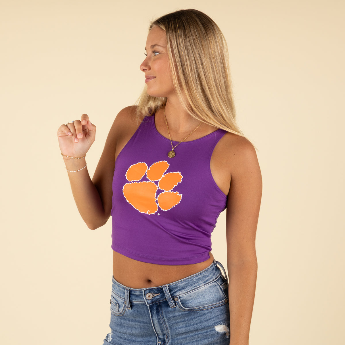 Woman in a purple Clemson crop tank featuring an orange paw print, smiling to the side.