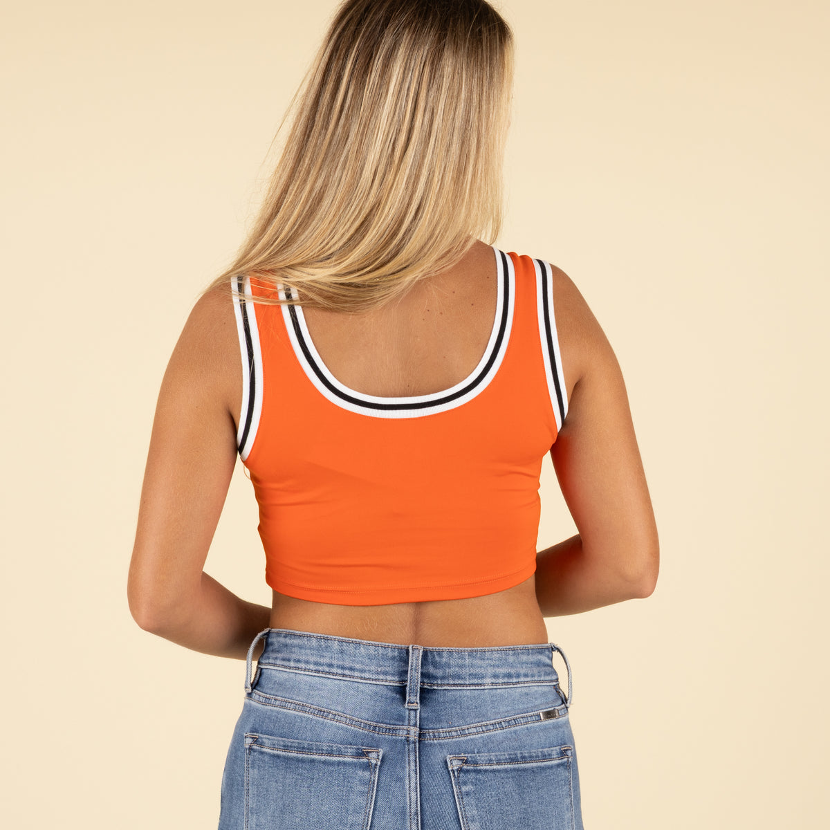 Back view of woman wearing the same orange Clemson cropped tank top with white and black striped trim.