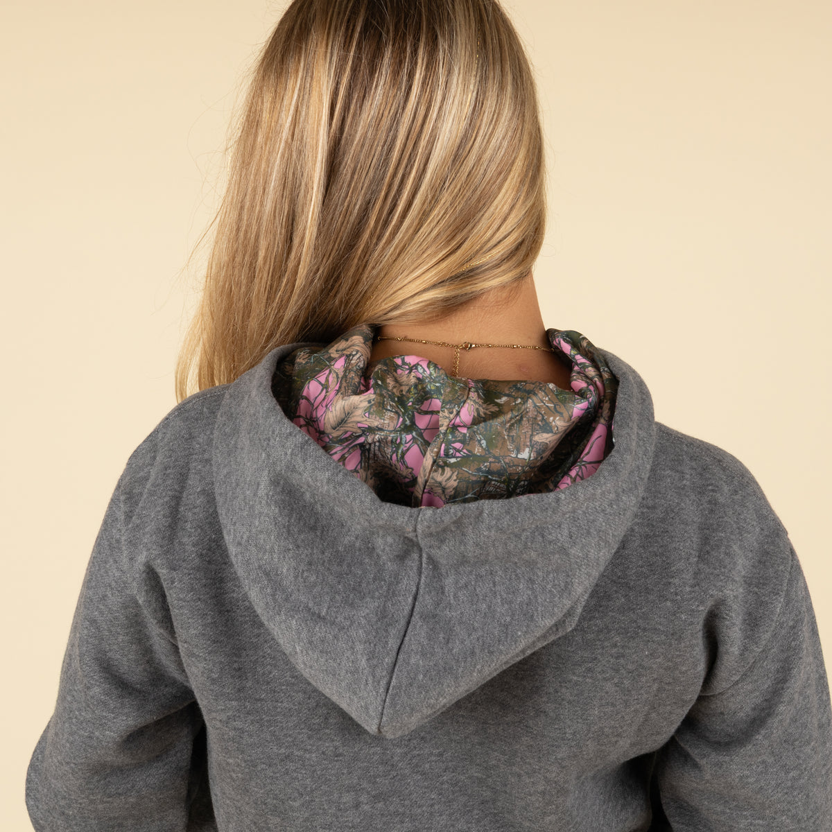 Back view of the hoodie with the hood up, showing the pink and camo lining detail.