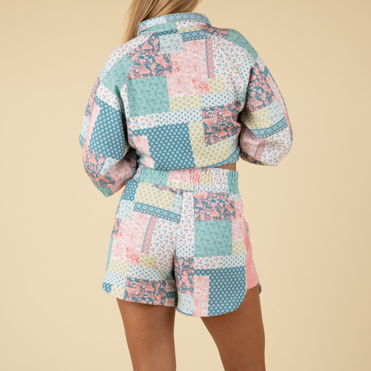 Back view of pastel patchwork-print shorts with an elastic waistband and pink side panels.