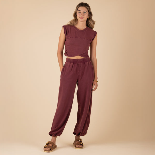 Woman Wearing Free People Movement Hot Shot Crossover Set, color clove, sizes XS-L, machine washable, 95% cotton, 5% elastane
Soft, jersey fabrication; relaxed fit; cropped muscle tee top with seaming detail; ankle length pant with high-rise waist and wide leg; elasticated waistband and cuffs; crossover detail on top; ribbed collar; side seam pockets