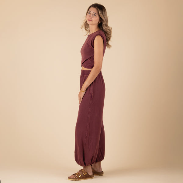 Woman Wearing Free People Movement Hot Shot Crossover Set, color clove, sizes XS-L, machine washable, 95% cotton, 5% elastane
Soft, jersey fabrication; relaxed fit; cropped muscle tee top with seaming detail; ankle length pant with high-rise waist and wide leg; elasticated waistband and cuffs; crossover detail on top; ribbed collar; side seam pockets