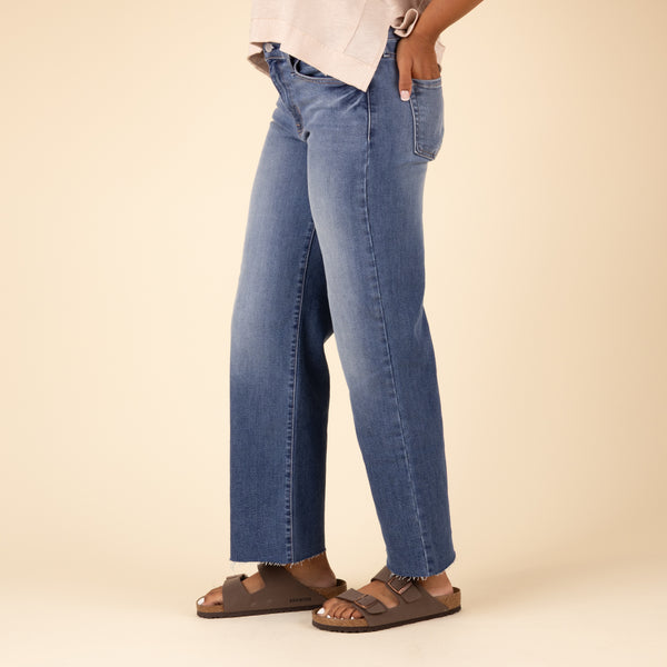 Side angle of Just Black Denim Palazzo Jeans in medium wash, showing front pockets and frayed hem. Model has one hand in pocket.