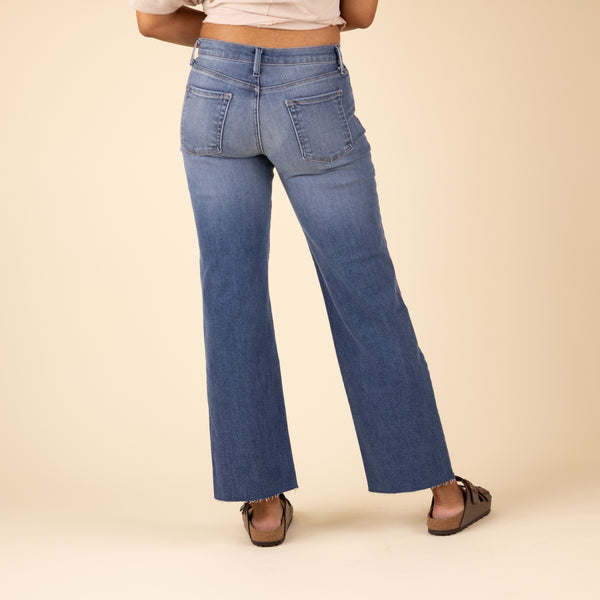 Back view of Just Black Denim Palazzo Jeans in medium wash, showing wide-leg fit, patch pockets, and raw hem. Model wears brown Birkenstock sandals.