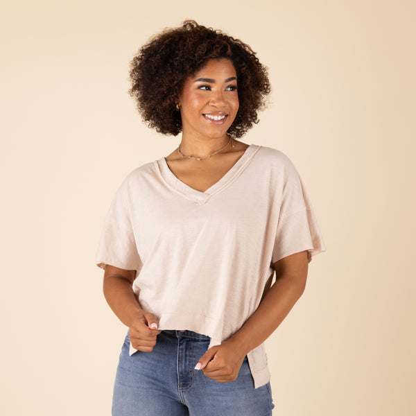  Woman wearing a beige top and blue jeans against a beige background