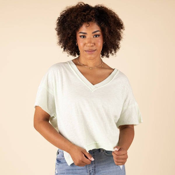 Woman wearing a white t-shirt and blue jeans against a beige background